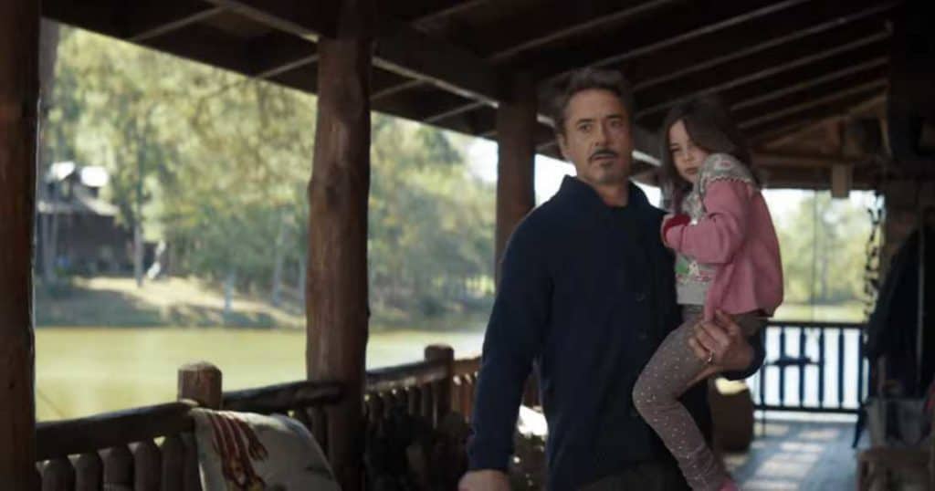 Robert Downey Jr. as Tony Stark in a scene from Avengers: Endgame, seen standing on the porch of his cabin and holding his little girl, Morgan. 