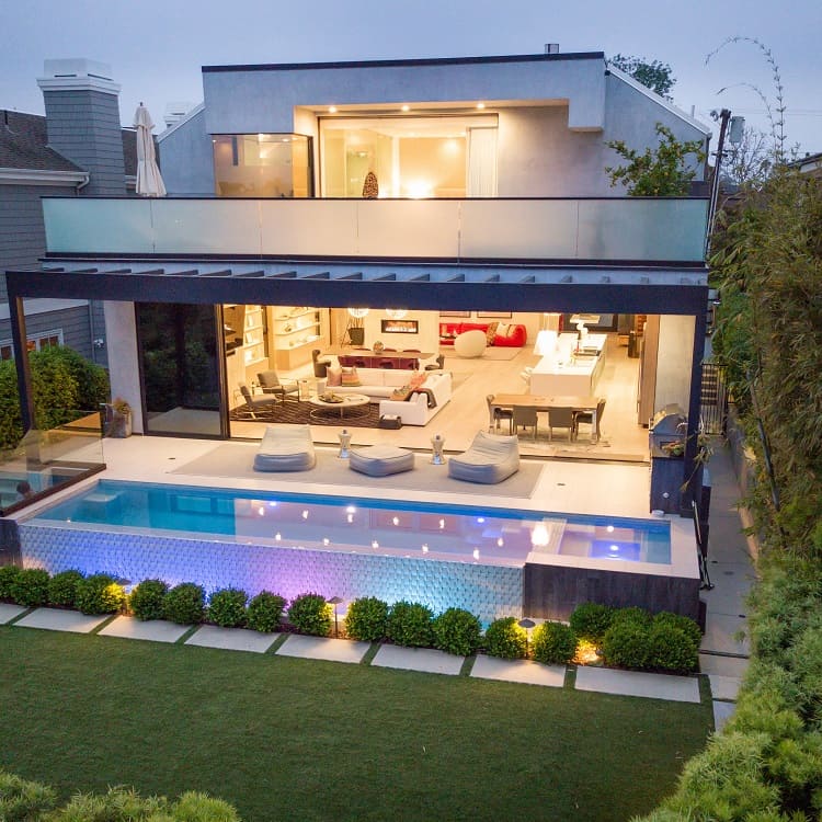 modern mansion with sliding doors opening the living room to the pool area