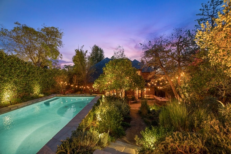 Walton Goggins' house has a whimsical backyard with two outdoor dining areas, a pool, and a fire pit. 