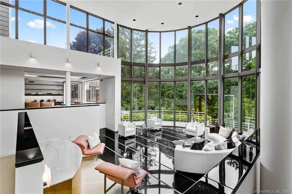 The dramatic living room has a two-story tall glass wall that serves as a backdrop to the living area. 