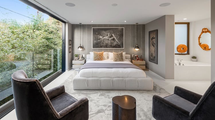The inviting main bedroom has walls of glass opening up to nature views that also bring in plenty of natural light.