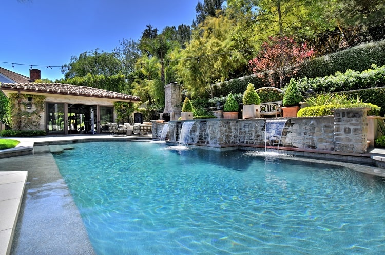 luxury pool with stone waterfalls and pool house