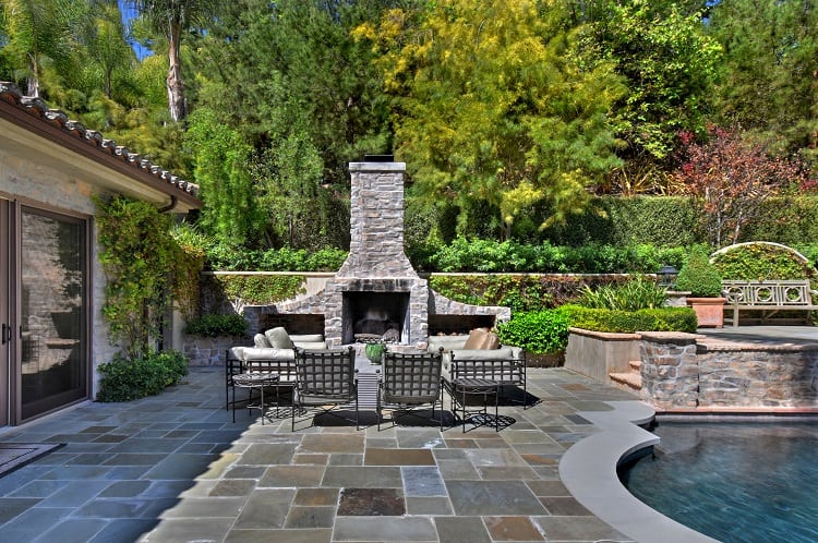 beautiful backyard with a stone fireplace next to the pool