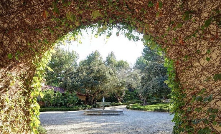 gravel motorcourt that features a stone fountain