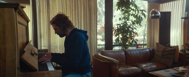 Jackson Maine playing a song at the piano, inside his lovely mid-century home.