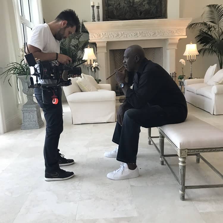 A behind-the-scenes photo taken while filming the Netflix documentary The Last Dance, showing Michael Jordan smoking a cigar with a cameraman filming him