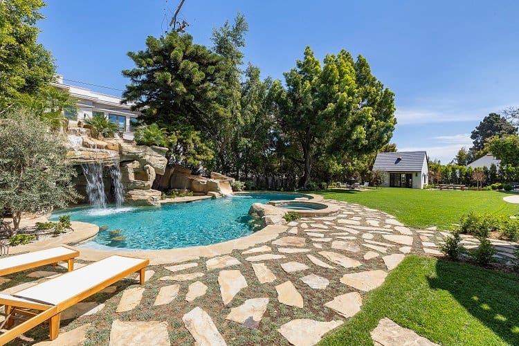 outdoor pool with stone pathways and waterfall