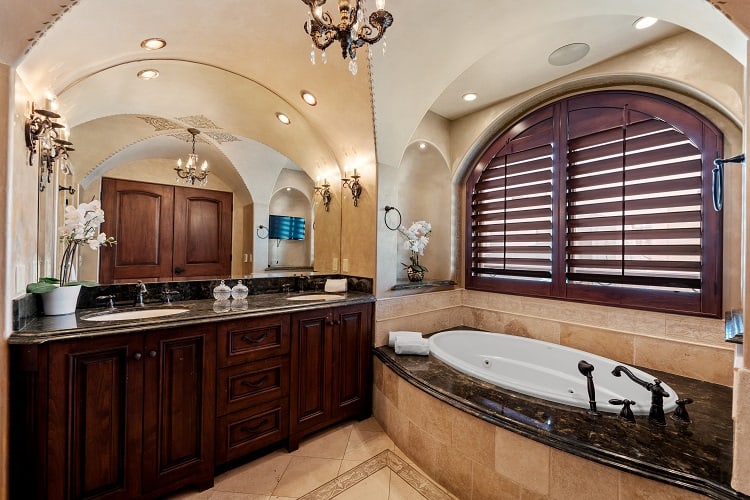 ultra-luxurious bath with dark wood elements, soaking tub, and chandelier