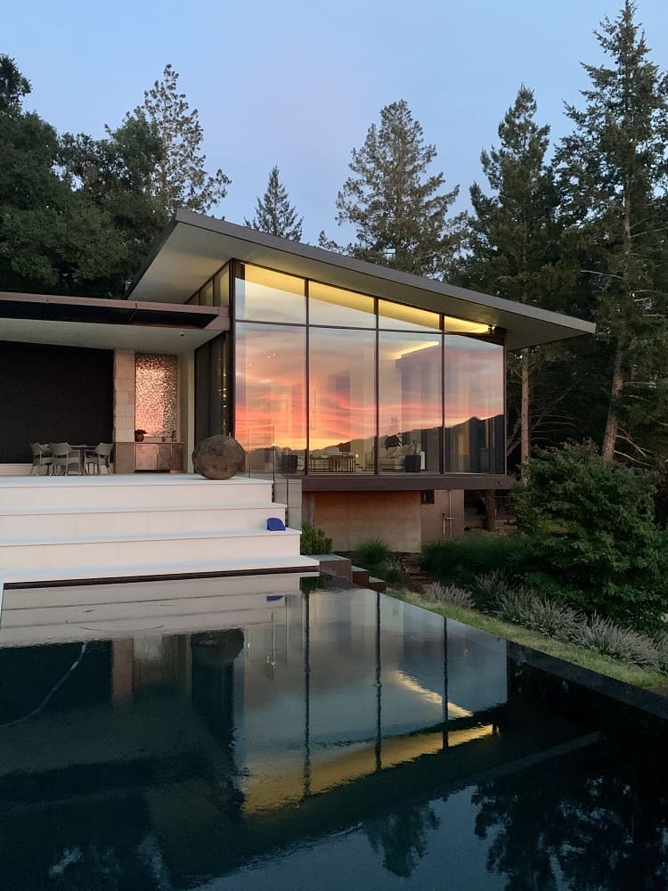 modern glass house with pool in front