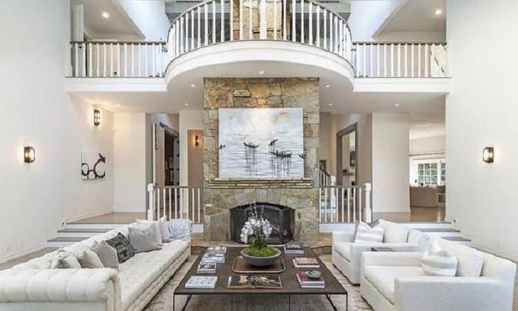 Living room inside Selena Gomez's house, anchored by a stone fireplace with artwork in the middle