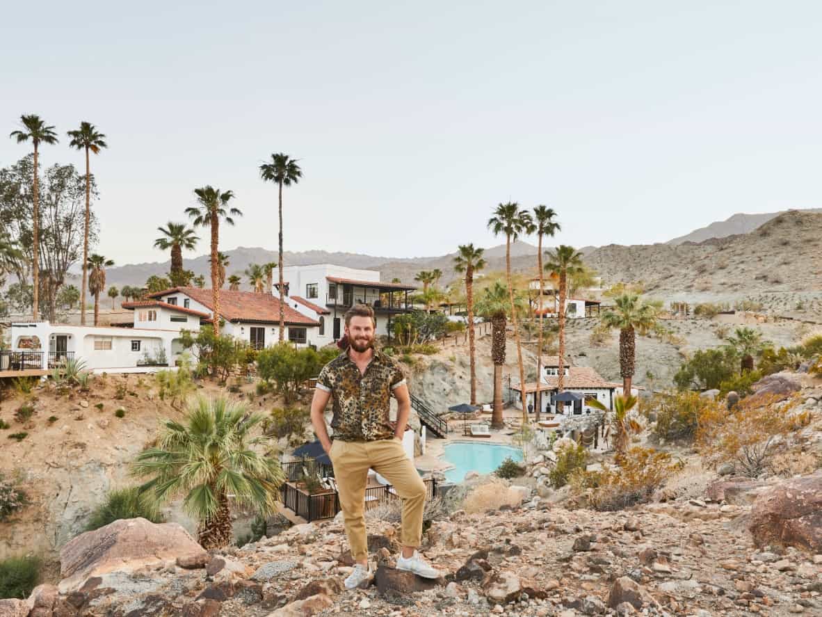 "Queer Eye" star and interior design expert poses in front of his stunning desert home for his debut as an Airbnb host.