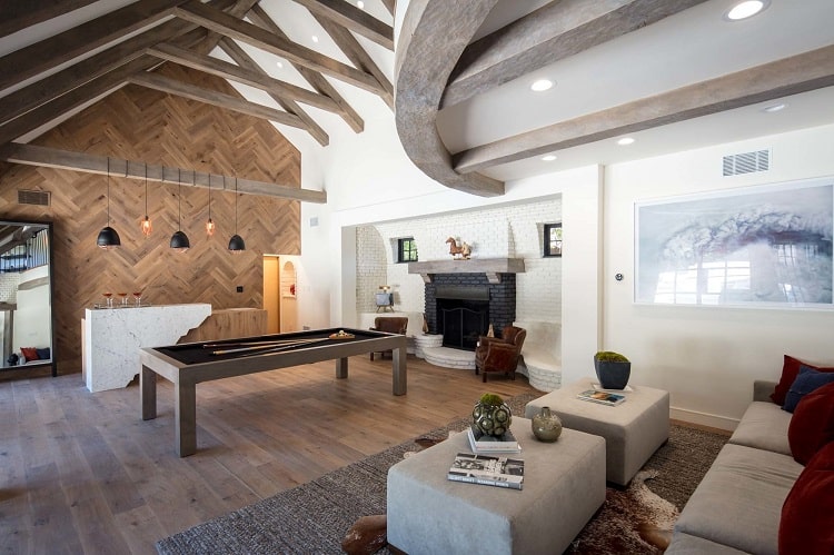 game room with fireplace and wood beams inside Machine Gun Kelly's house