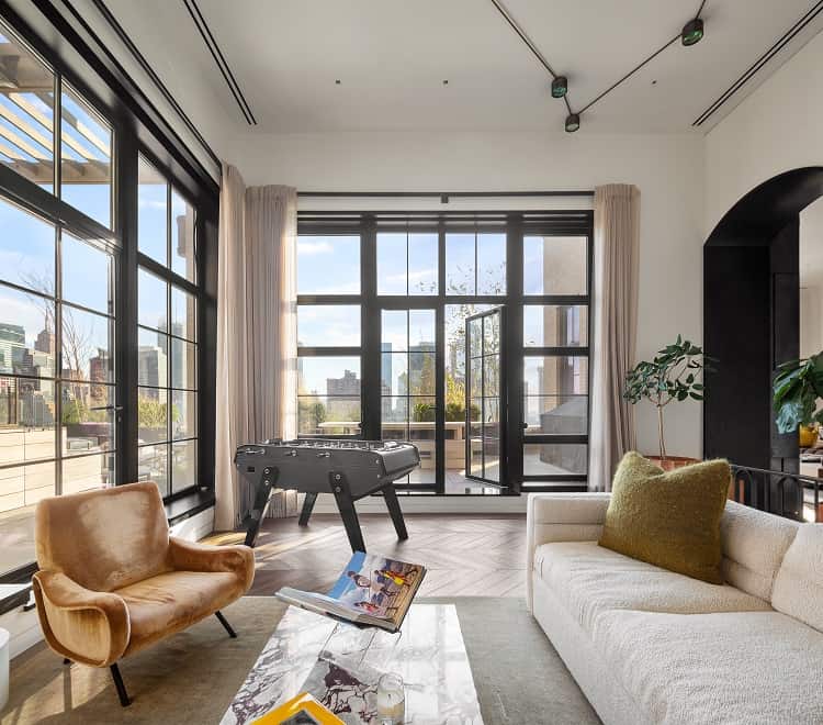 den with walls of windows and foostable inside Trevor Noah's penthouse