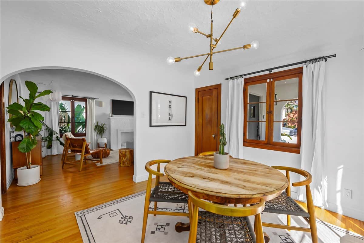 dining room with arched entrance, dining table, light fixture and window