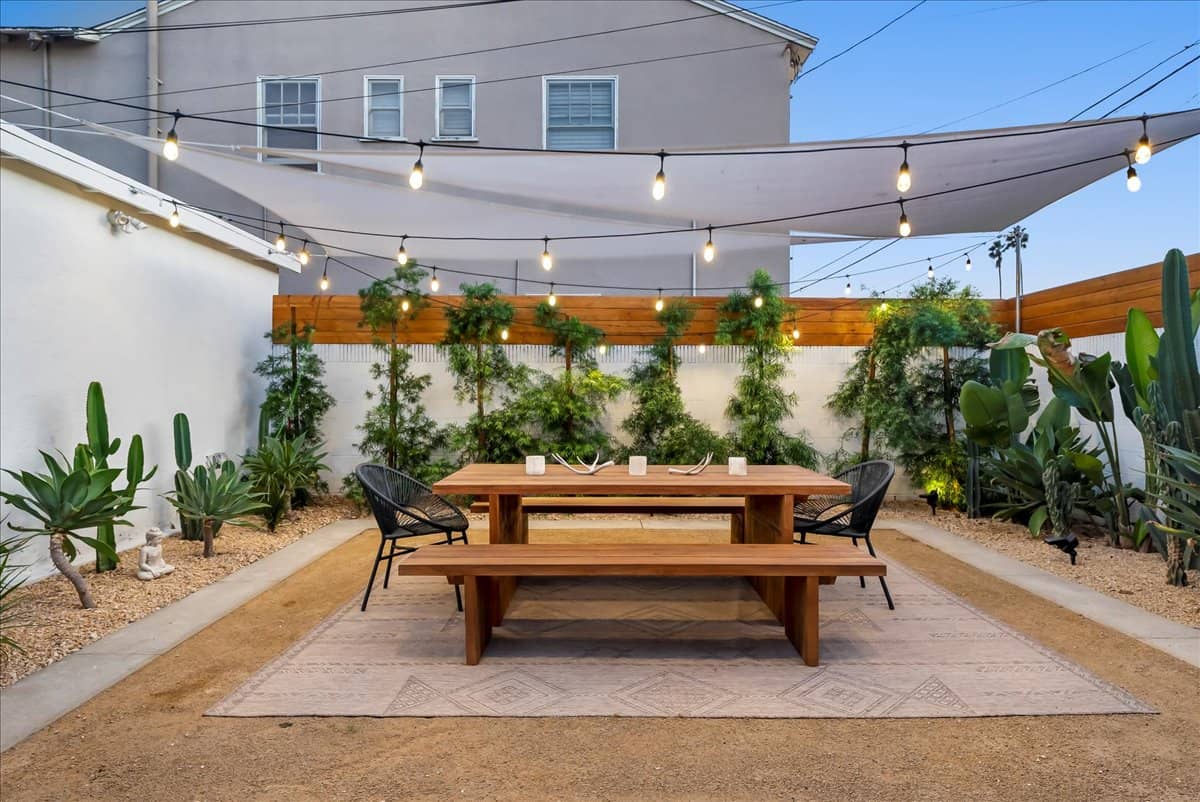 benches and table in a backyard covered with fairy lights