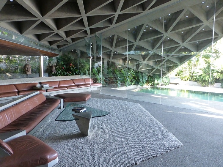 Inside Lautner's Sheats-Goldstein residence, anchored by two brown leather sofas set in front of a wall made entirely out of glass with the pool in the background.