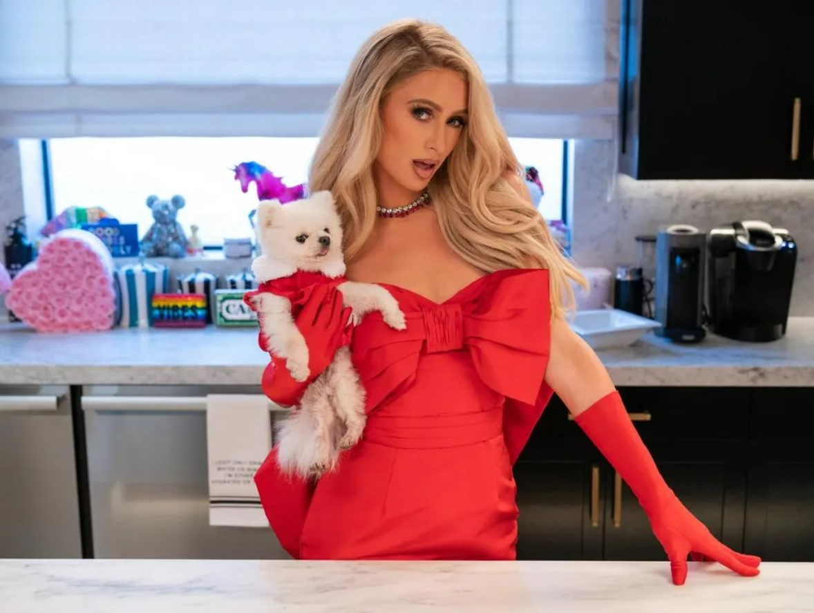 Paris Hilton wearing a red bow dress in a promotional photo for her Netflix show, Cooking with Paris, filmed inside her Malibu home.