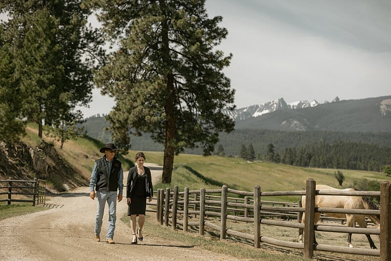 Kevin Costner walking alongside a woman on the Yellowstone ranch