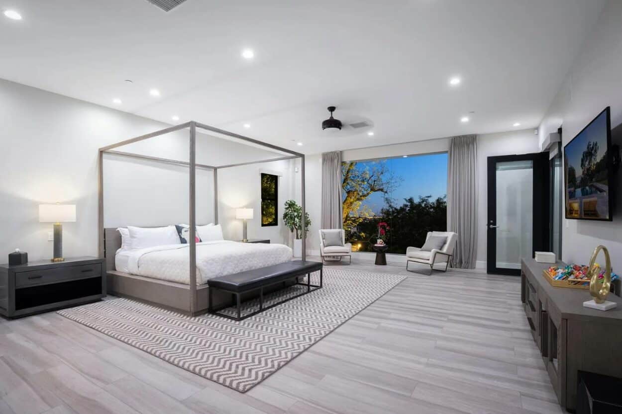 The primary bedroom suite inside Bad Bunny's house, with a four-poster bed and glass balcony