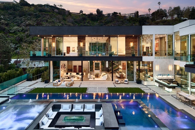 An ultra modern Bel Air mansion with walls of glass and two sets of pools, with a fire pit seating area in the middle 