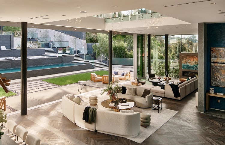 living area with couches next to a wall of glass that shows the backyard