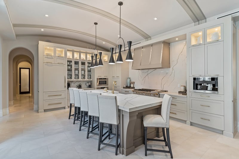 kitchen with mostly white furniture, marble island, and tufted bar stools