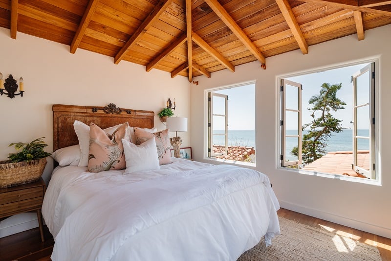 bedroom with vaulted wood ceilings and open windows with ocean views