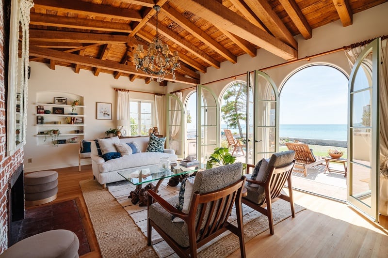 living room with vaulted ceilings with exposed wood and arched glass doors leading to the ocean