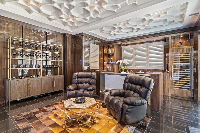 luxury bar and entertainment room with intricate ceilings, a glass cabinet, wine cellar and leather armchairs