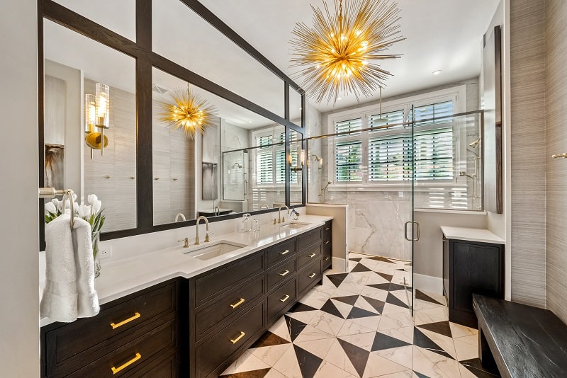 bathroom with dark wood furniture, white and black tiles, walk-in shower, and an eye-grabbing light fixture