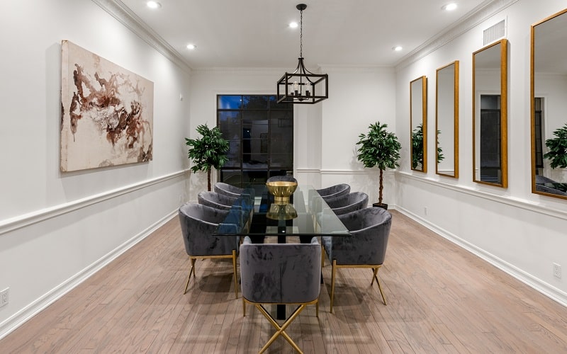 dining room with clear glass table, tufted dining chairs and several mirrors on the wall