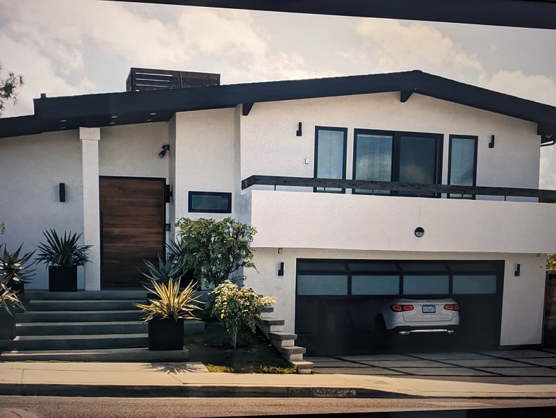 Screen grab of Amy Lau's house in 'Beef', a large white house with a two-car garage and a dark-painted roof