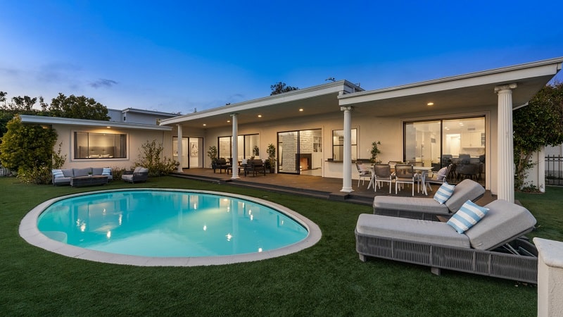 exterior of a Hollywood Regency-style residence with a round pool in front