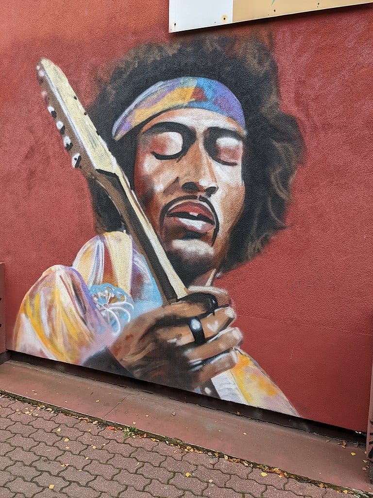 mural of jimi hendrix playing the guitar on a red background