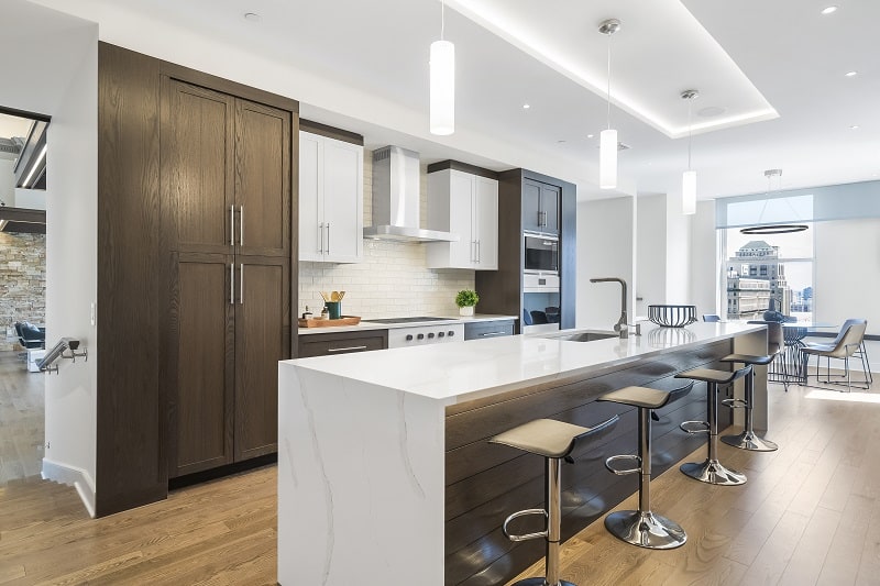 modern dark wood kitchen with white marble counter and bar stools