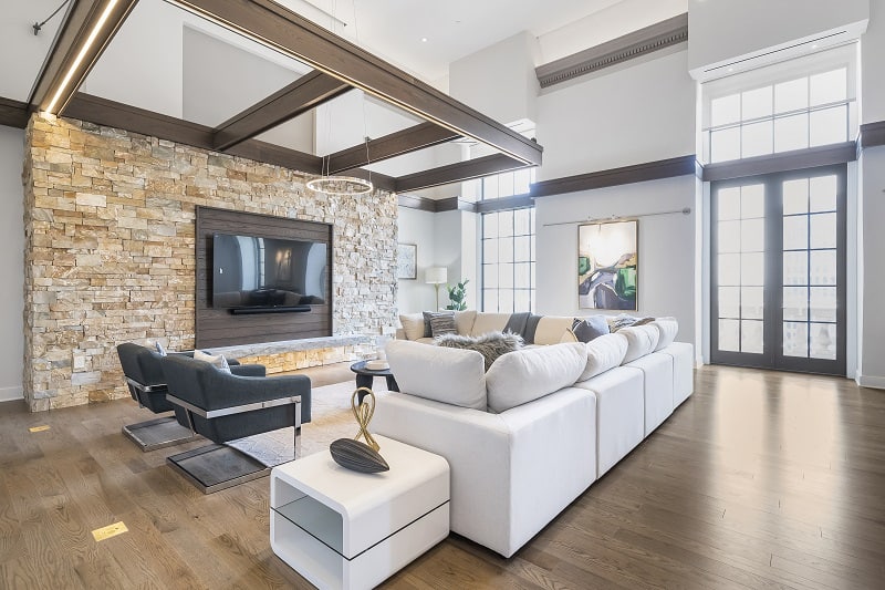 living room with TV, hanging chandelier, a white sofa and an accent wall