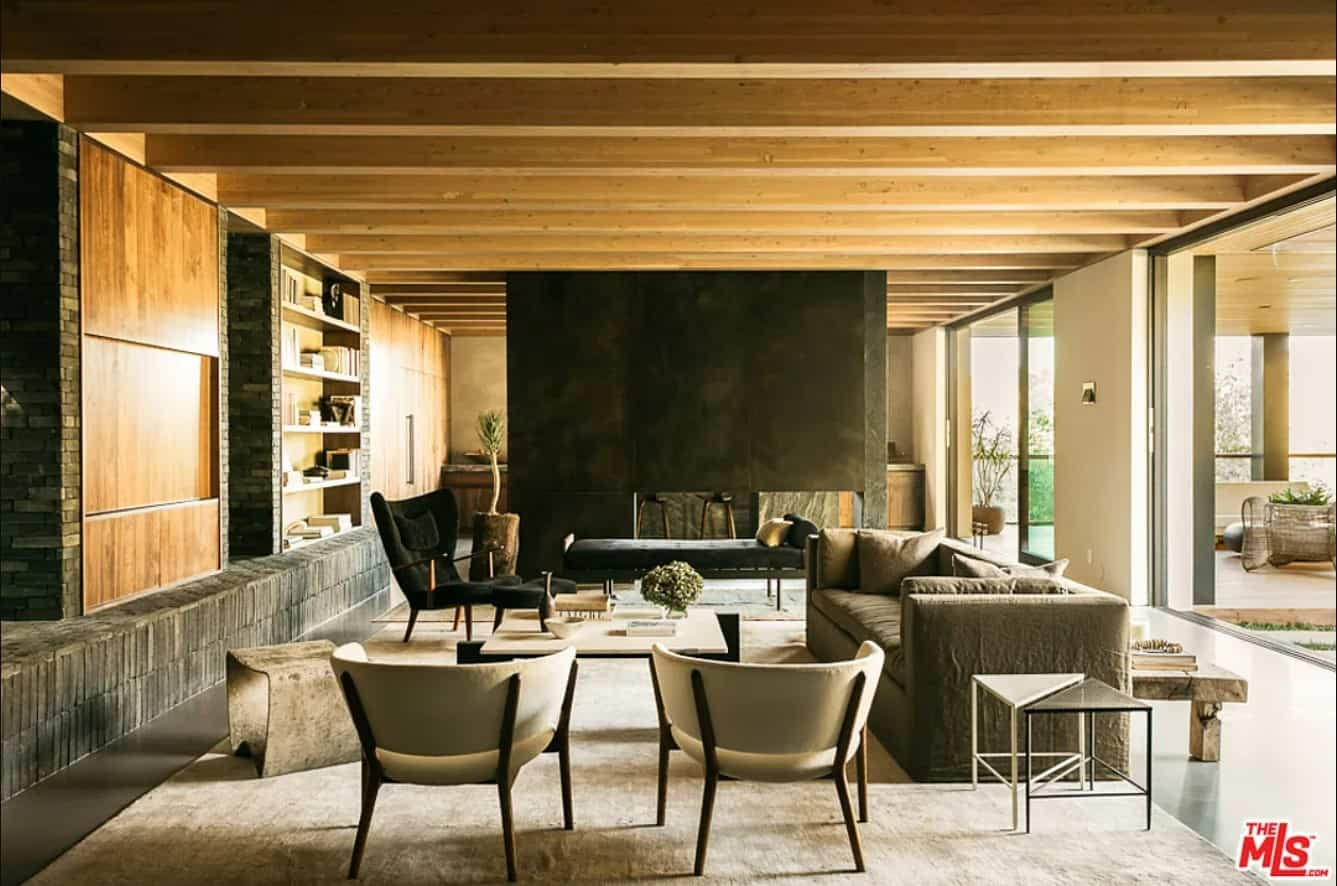 wood-clad interiors anchored by a large concrete fireplace with a sofa and arm chairs in front of it.