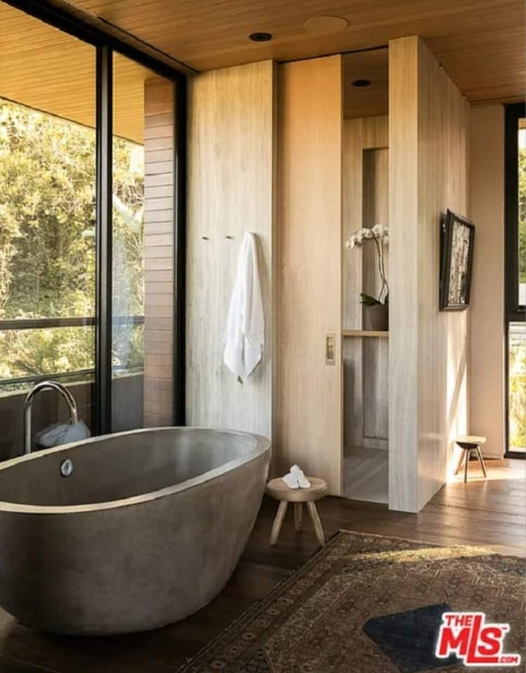 The bathroom mimicks the rest of the house's decor, being wrapped in warm wood and anchored by a concrete soaking tub. 