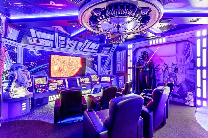 Star Wars-themed home theater with R2-D2, Darth Vader figurines, movie theater chairs, and a large TV 