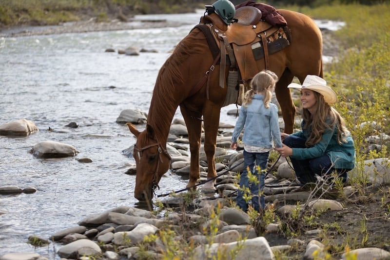 Heartland Episode 1501: Amy (Amber Marshall) and Lyndy (Ruby and Emmanuella Spencer) at the stream with their horse