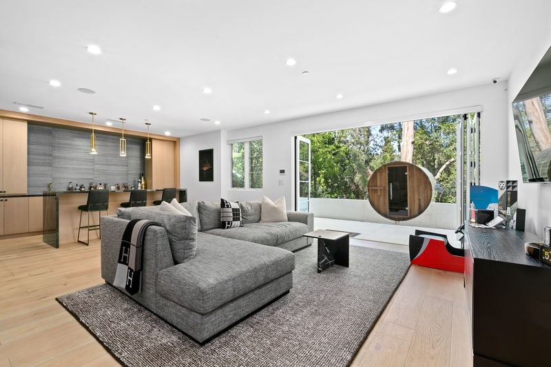 basement lounge with wet bar, sofa and balcony doors leading to a barrel sauna