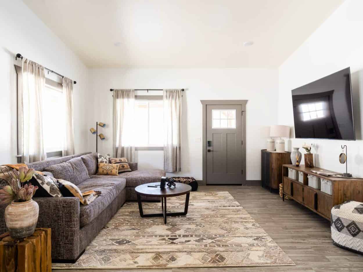 caretaker apartment decorated simply with a grey couch, cream rug and a mounted TV 