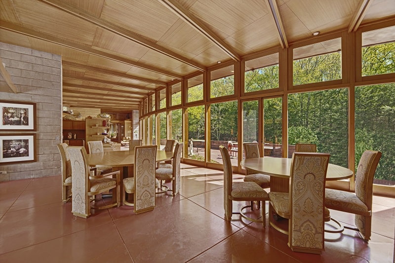 dining room with two dining sets and large floor-to-ceiling windows, everything made out of warm wood