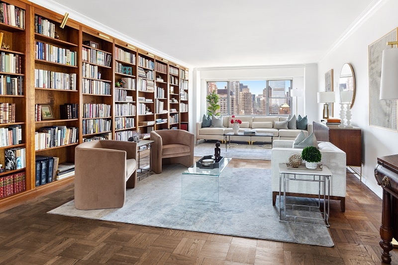 living room of a new york city apartment with one wall covered entirely by a bookshelf