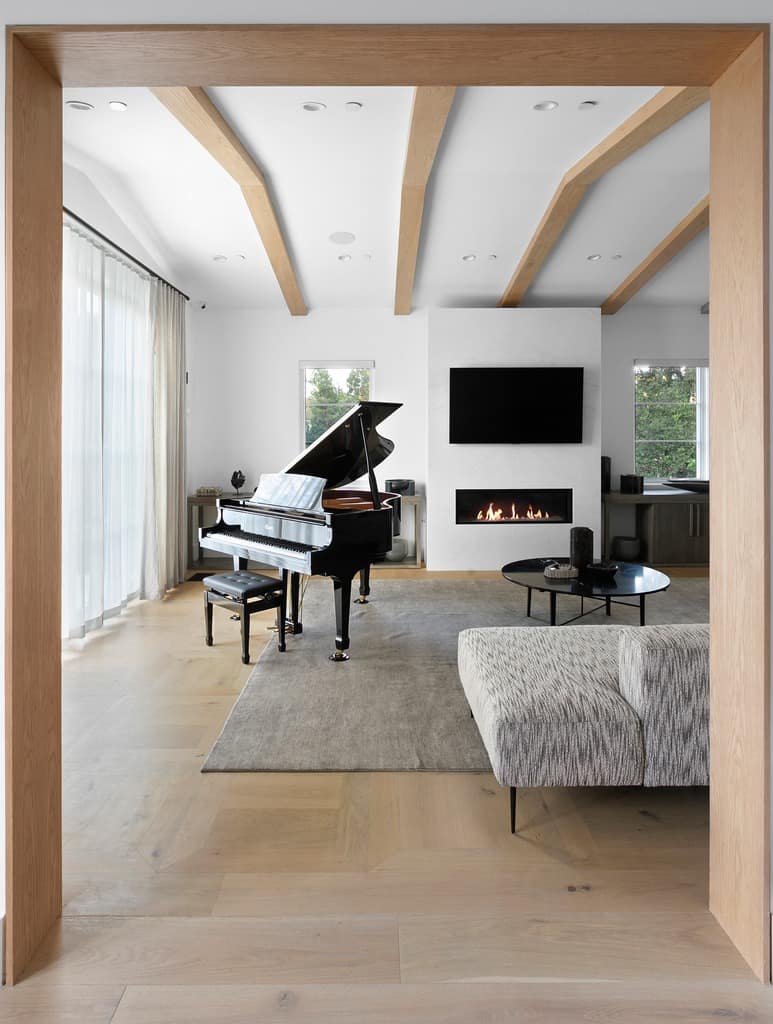 living room entrance showing the black piano, fireplace with TV mounted above it and sofa with coffee table