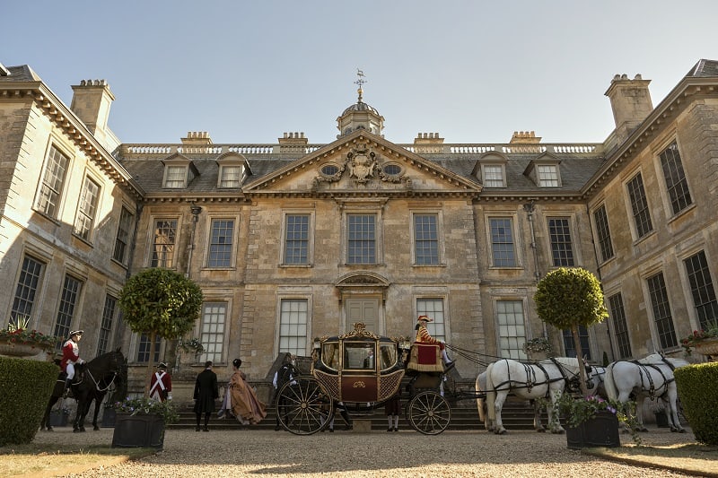 India Amarteifio as Young Queen Charlotte getting down from a carriage in front of King George's Kew Palace in episode 105 of Queen Charlotte: A Bridgerton Story.