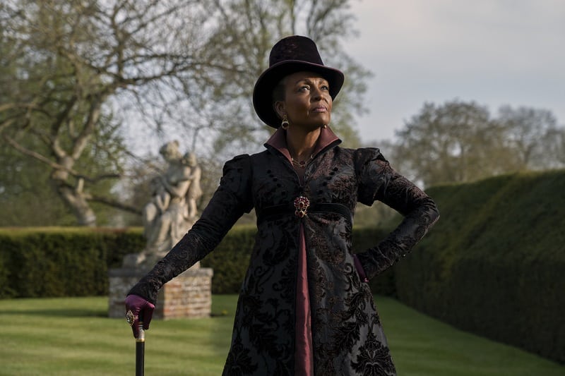 Adjoa Andoh as Lady Agatha Danbury in episode 102 of Queen Charlotte: A Bridgerton Story, walking in the gardens of her estate