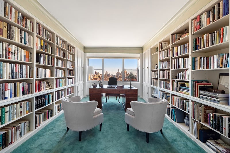 library with walls of books and a desk with armchairs