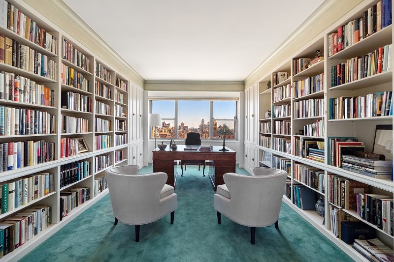 library with walls of books and a desk with armchairs 