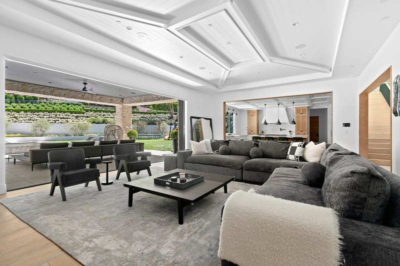 another view of the living room showing the outdoor area and kitchen in the background